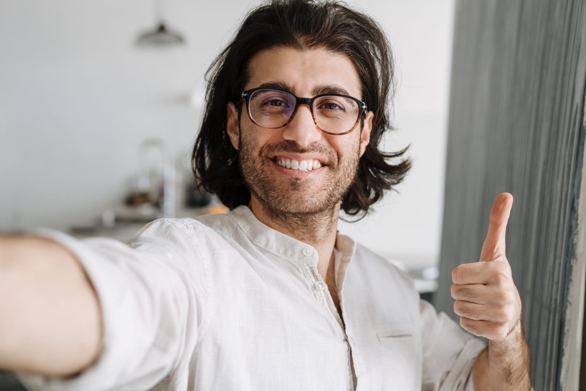 Młody mężczyzna z ciemnymi włosami robiący selfie.